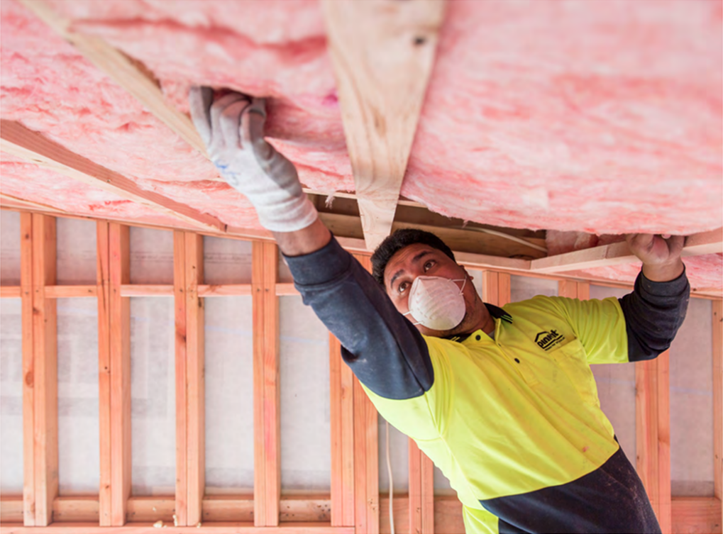 A Man Installing Pink Batts In A Ceiling — Austral Insulation In Toormina, NSW