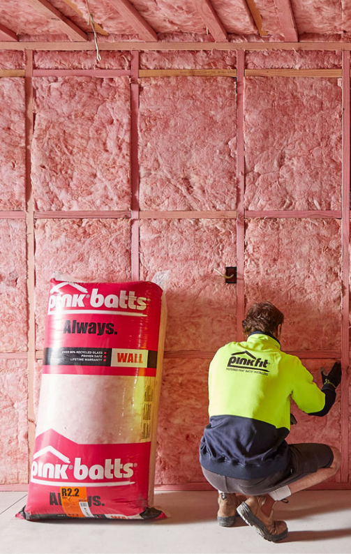 A Man In A Hi-Vis Installing Insulation Into A Wall — Austral Insulation In Toormina, NSW