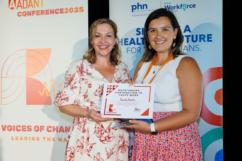 Two people standing side-by-side holding a certificate at the AADANT Conference 2025 in front of event banners.