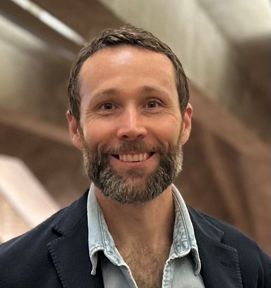 A woman wearing glasses and a green shirt is smiling