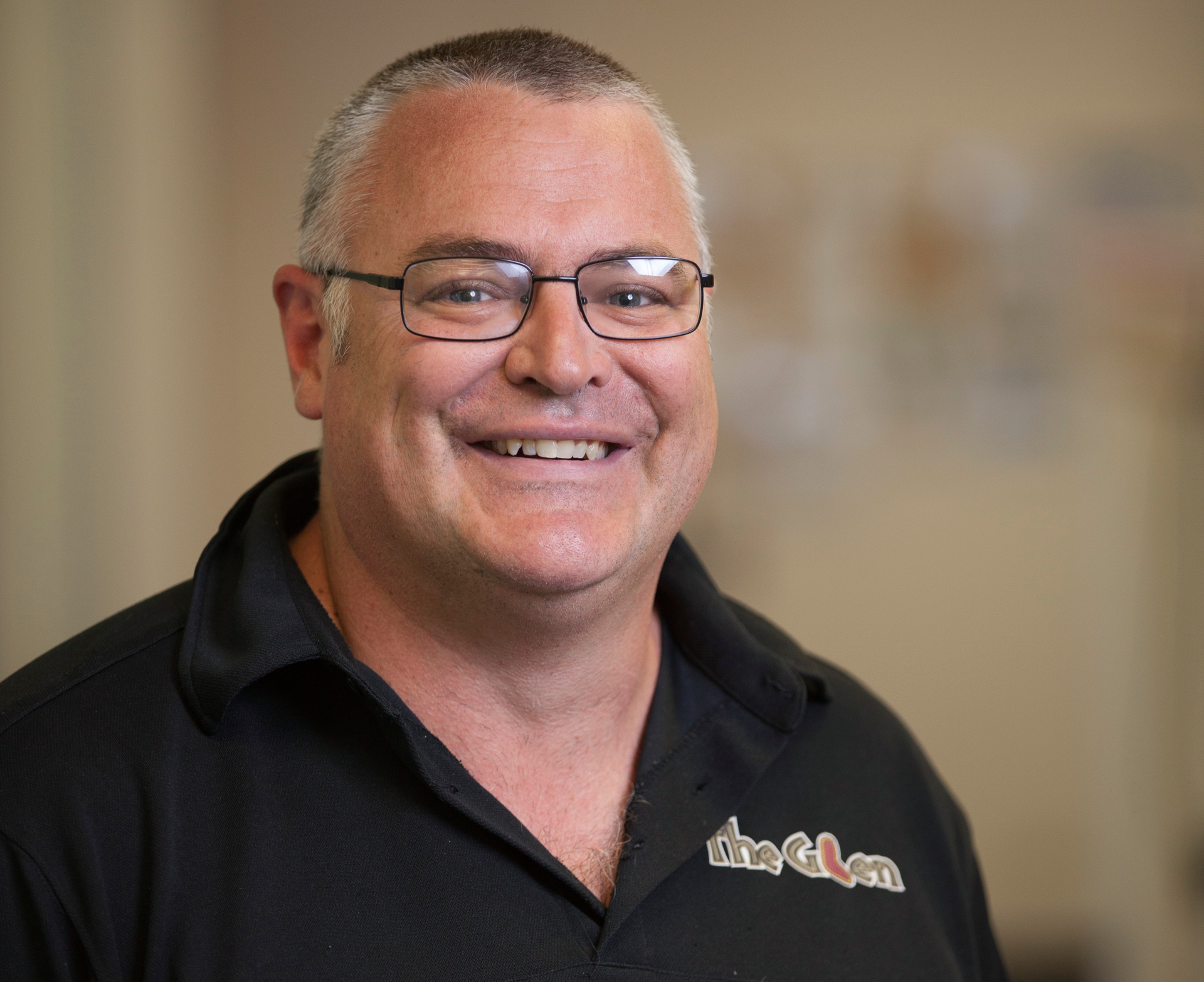 A bald man with a beard is wearing a blue shirt and smiling for the camera.