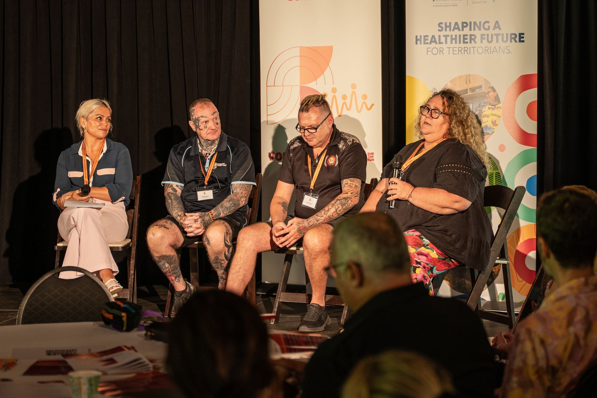 Four people sit in a panel discussion before an audience with 