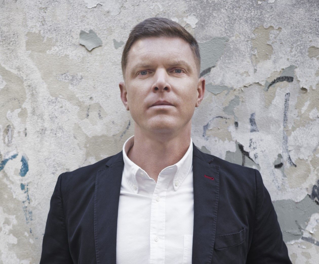 A bald man with a beard is wearing a blue shirt and smiling for the camera.