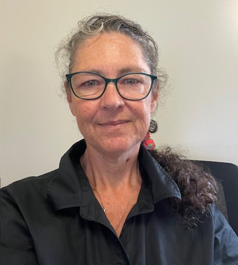 A bald man with a beard is wearing a blue shirt and smiling for the camera.