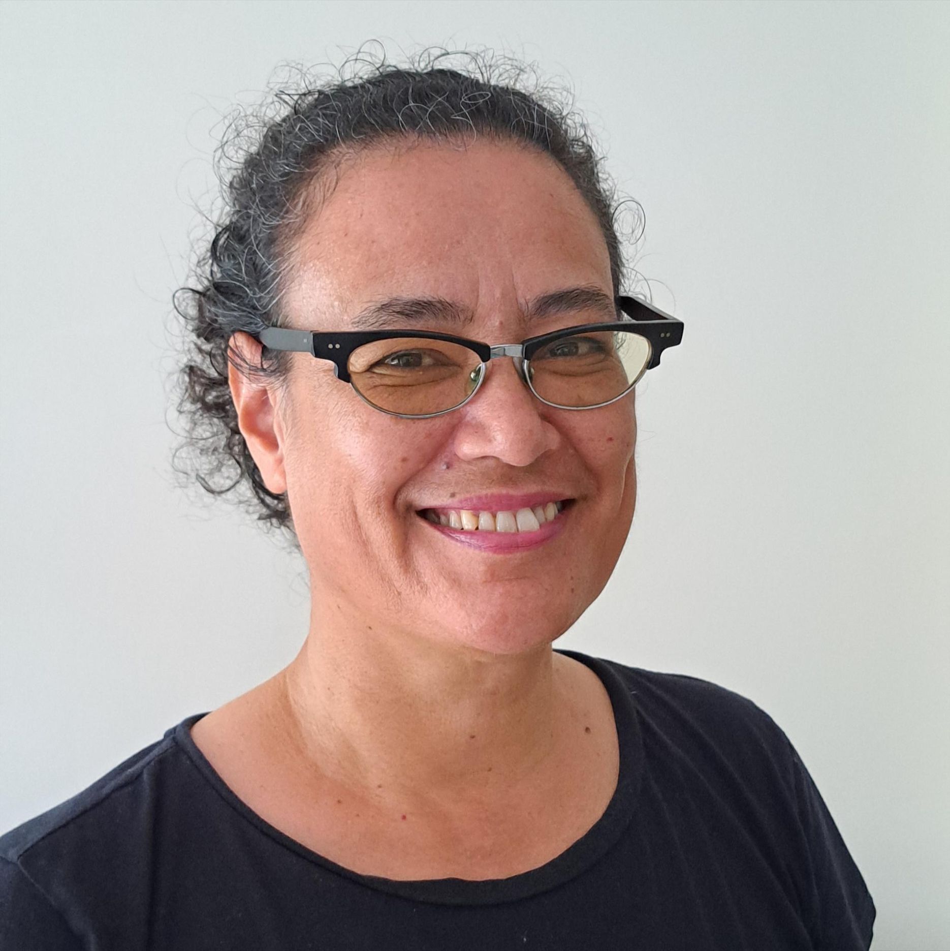 A woman wearing glasses and a black shirt smiles for the camera