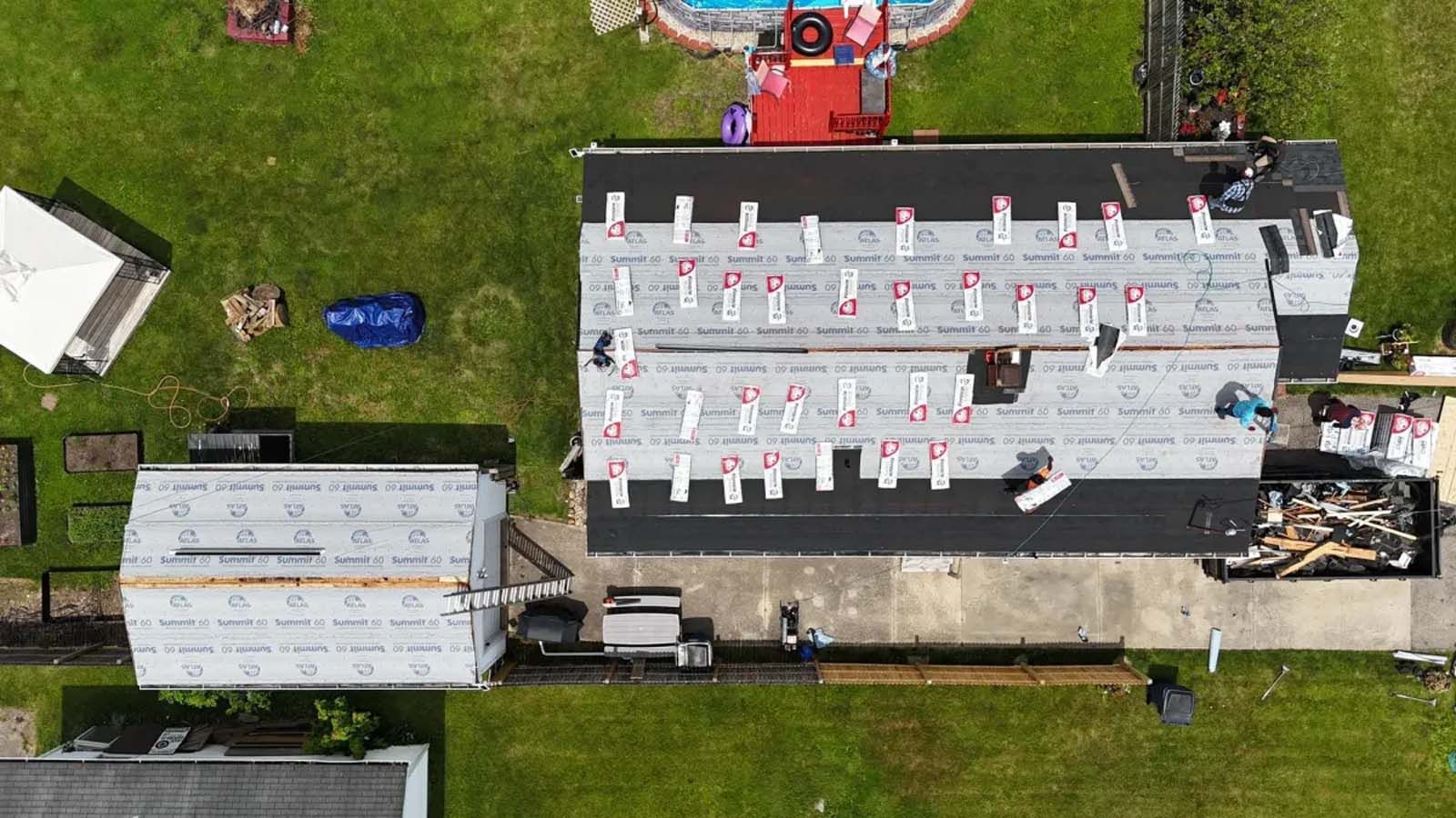 An aerial view of a house under construction with a pool in the background.