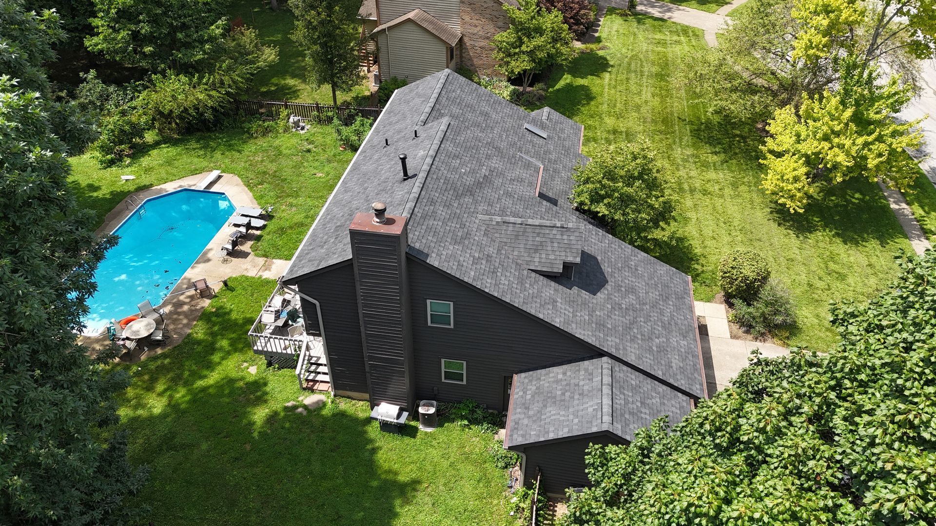 Aerial view of a dark house with a pool and lush green yard.