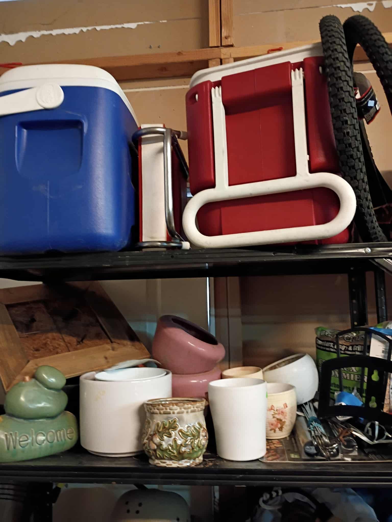 Shelf with coolers, planters, and a bicycle tire.