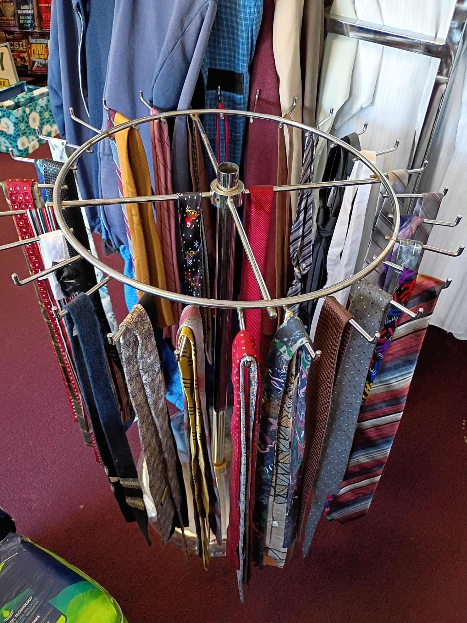 A round tie rack with many colorful ties hanging from it.