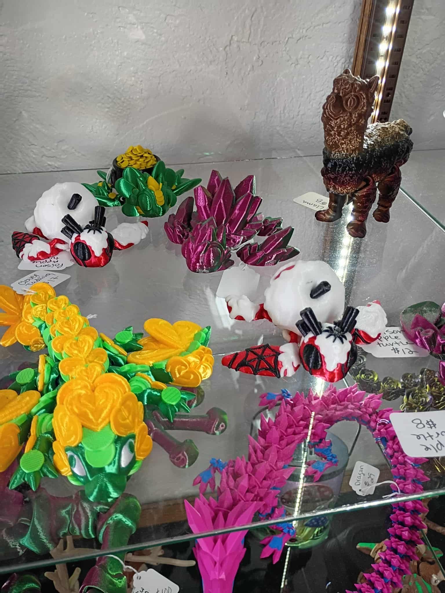 Display case with colorful 3D-printed creatures, including octopuses, a dragon, and crystalline shapes.