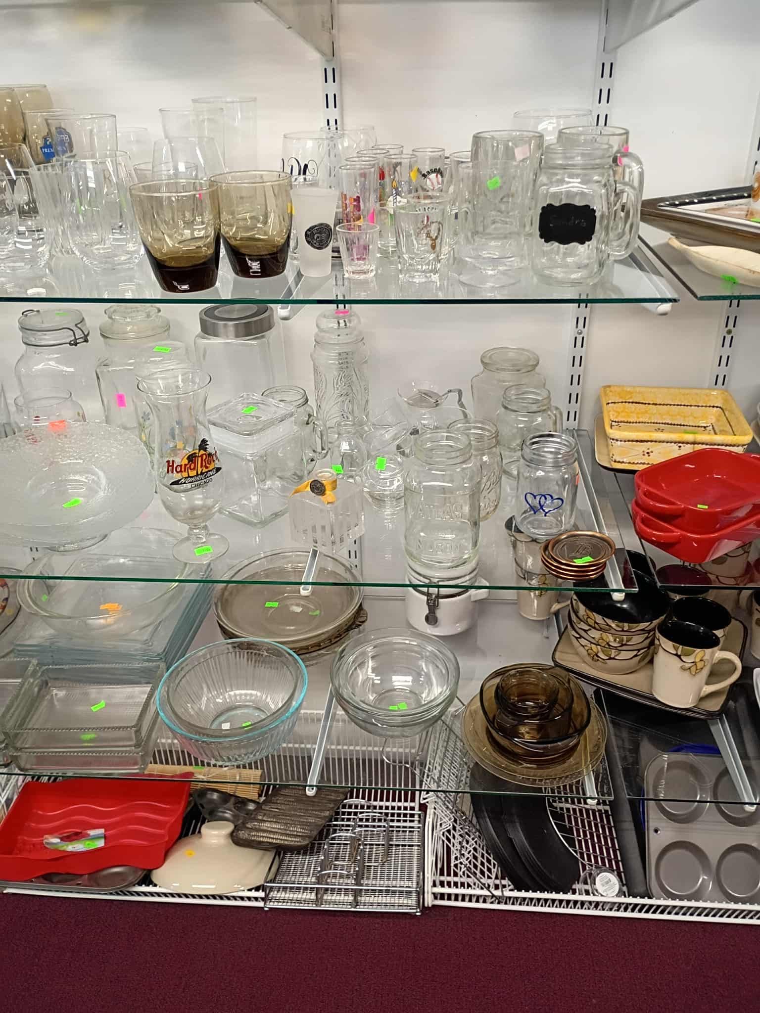 Glassware displayed on shelves in a store, including cups, bowls, and pitchers.