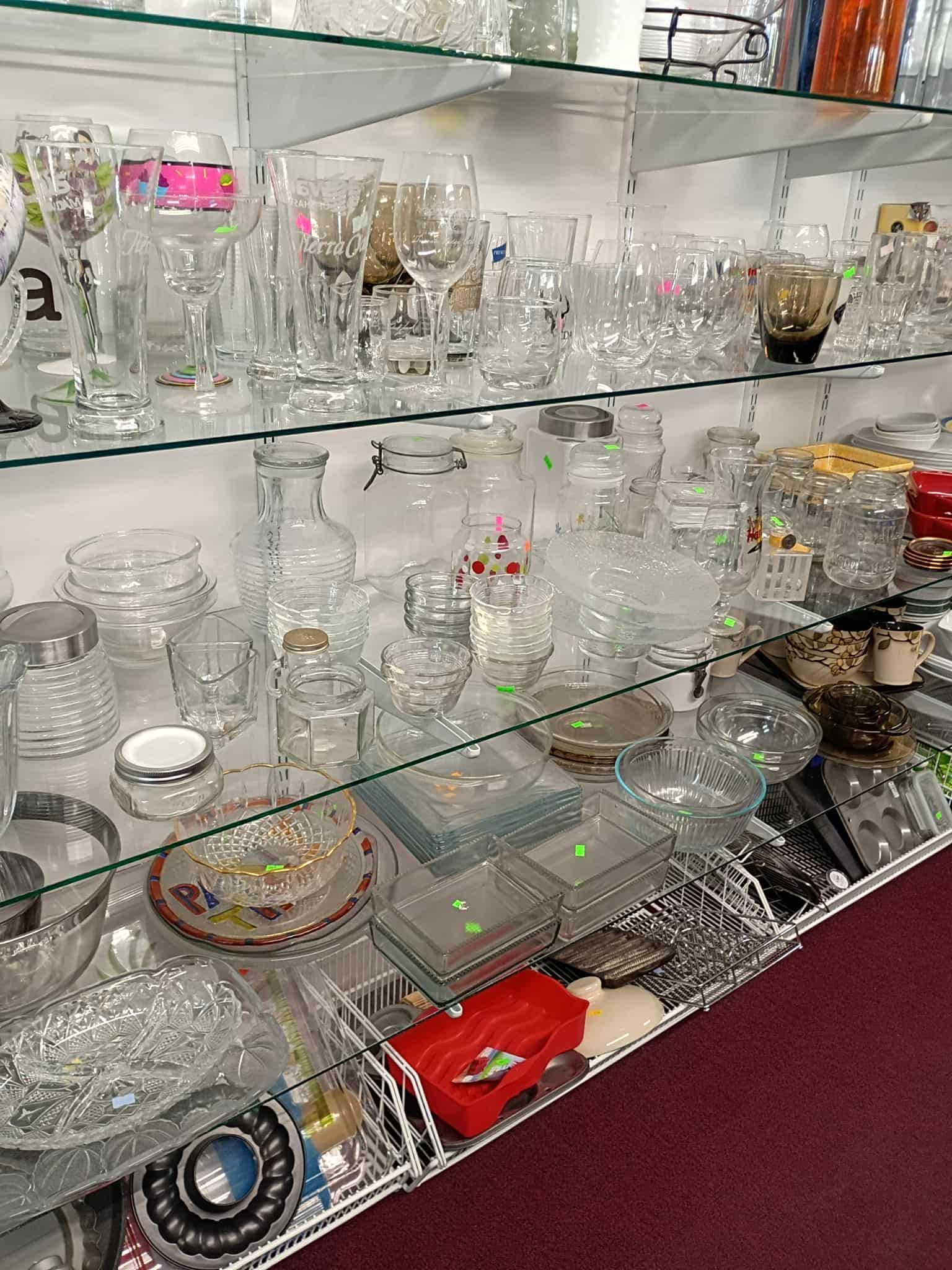 Glassware display on shelves in a shop, including glasses, bowls, and decorative items.
