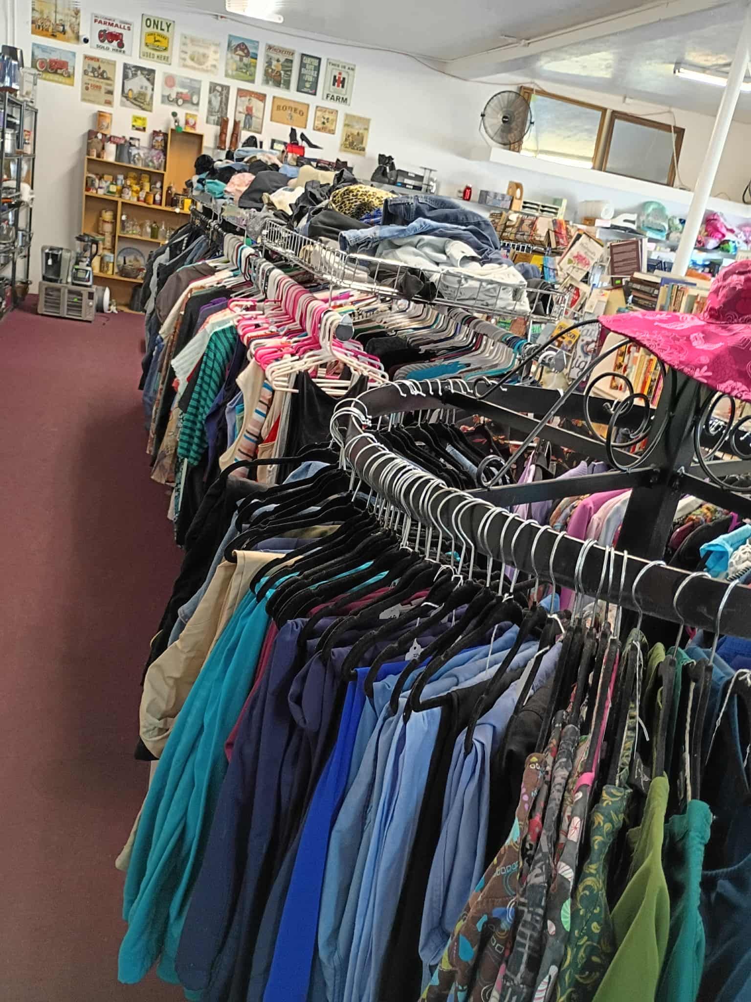 Clothing racks in a store; clothing is colorful and diverse.