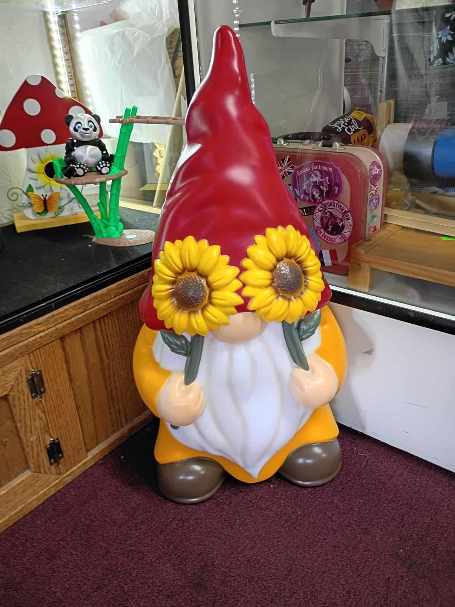 A garden gnome with a red hat and sunflower eyes.