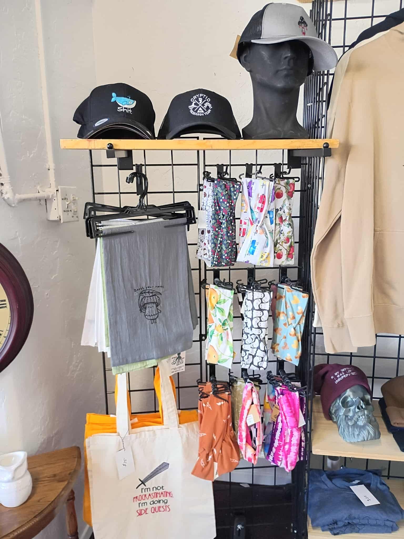 Shop display with hats, scarves, and tote bags; tan, black, and floral patterns.