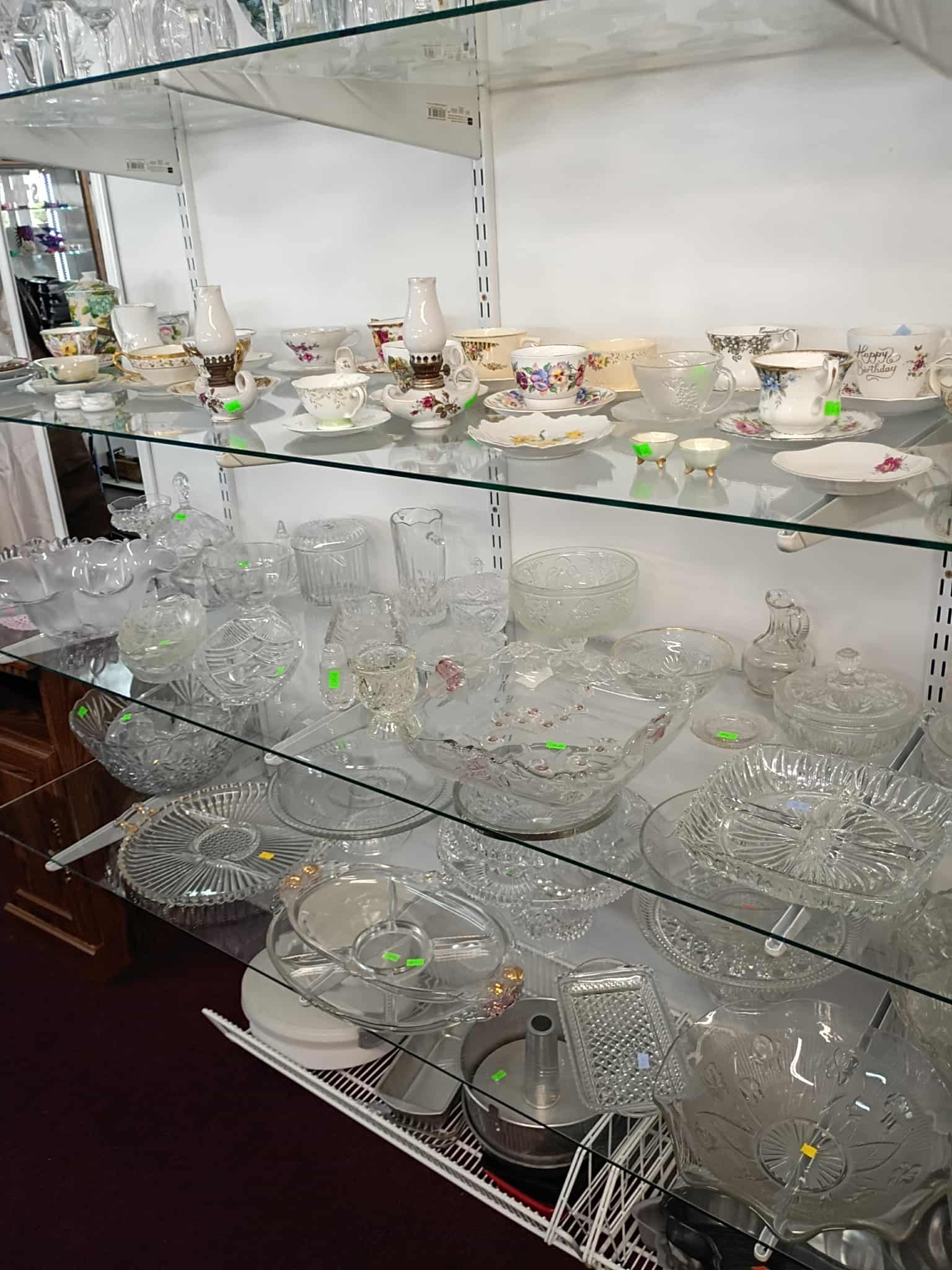 Glass shelves display vintage china and crystal bowls in a store setting.