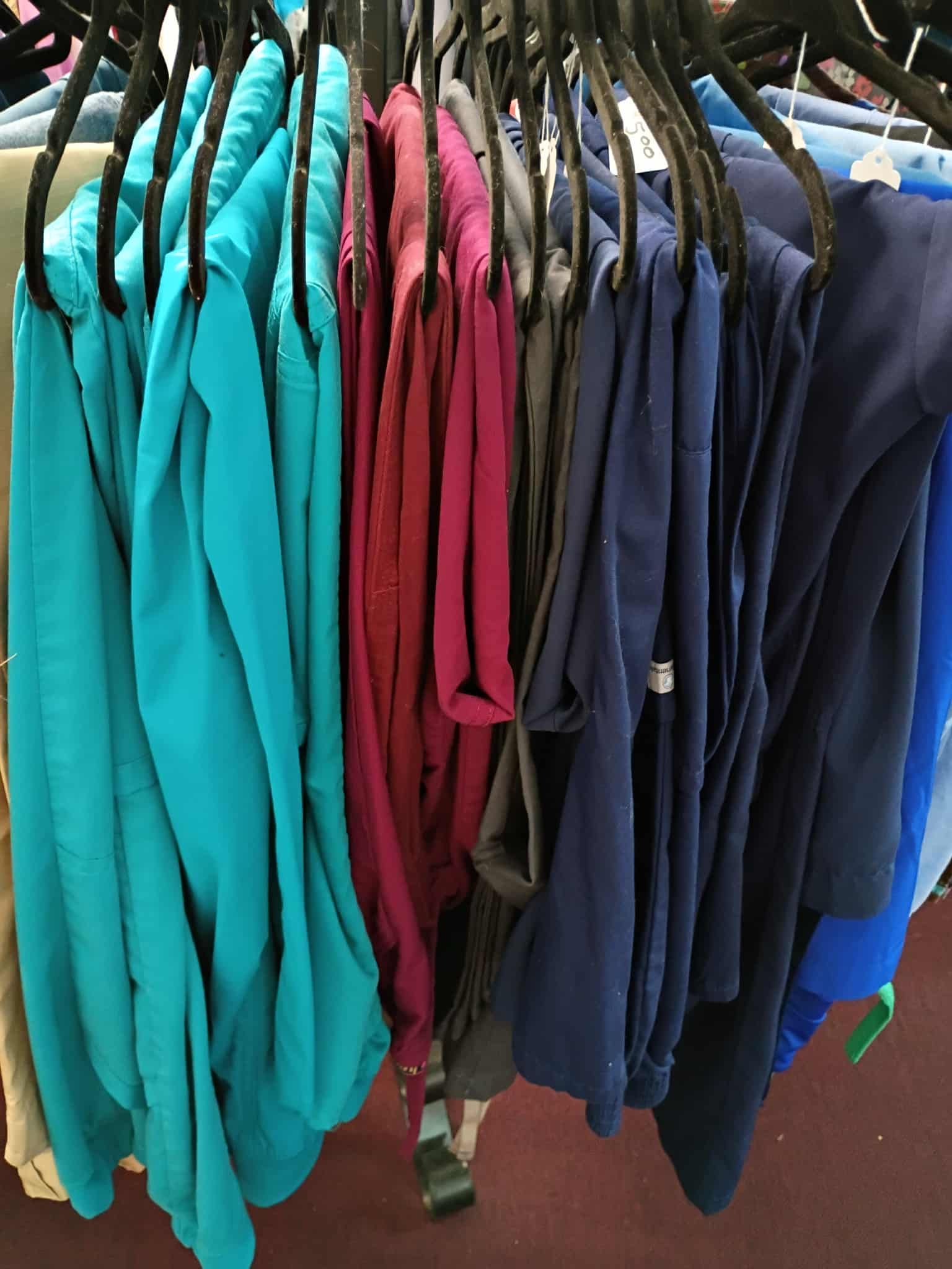 Clothes of various colors hanging on racks; blue, magenta, navy and black clothing items are visible.