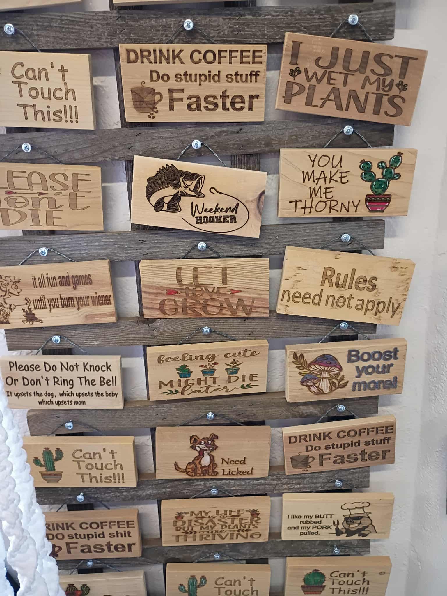 Wooden signs with humorous phrases are attached to a wooden pallet.