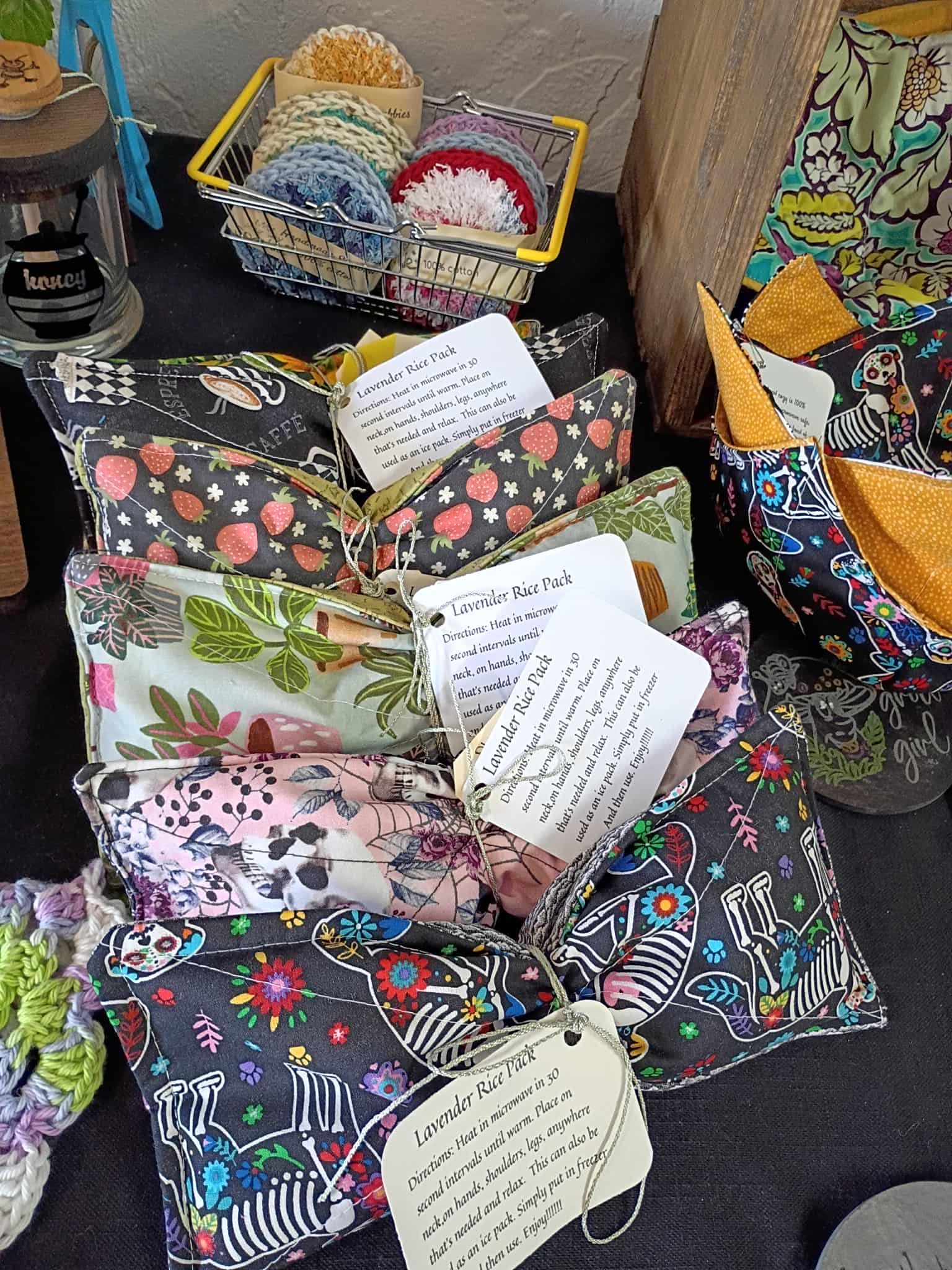 Fabric pouches with attached tags for sale at a market. Floral and patterned fabrics.