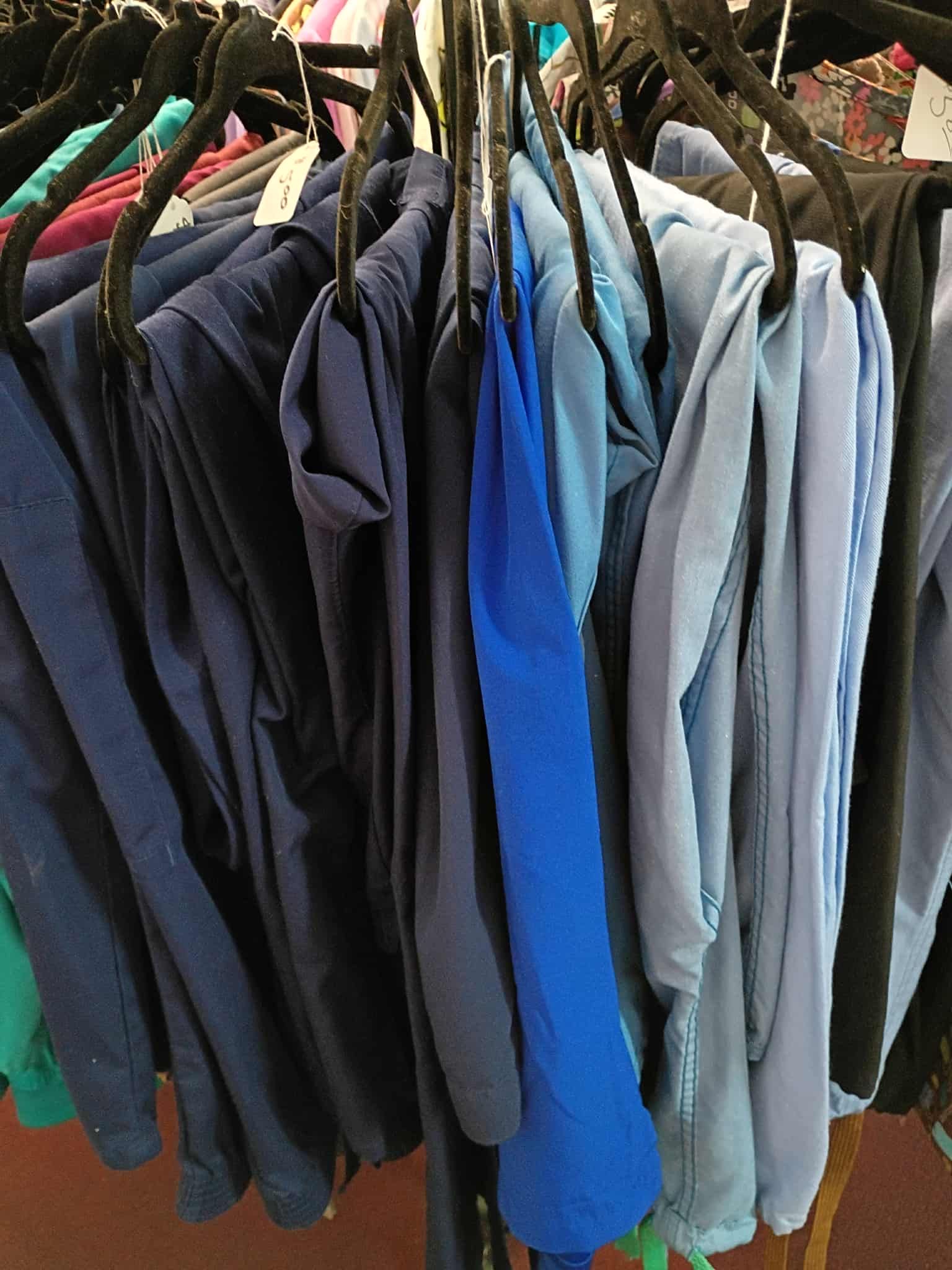 Clothes in various shades of blue hanging on black hangers.