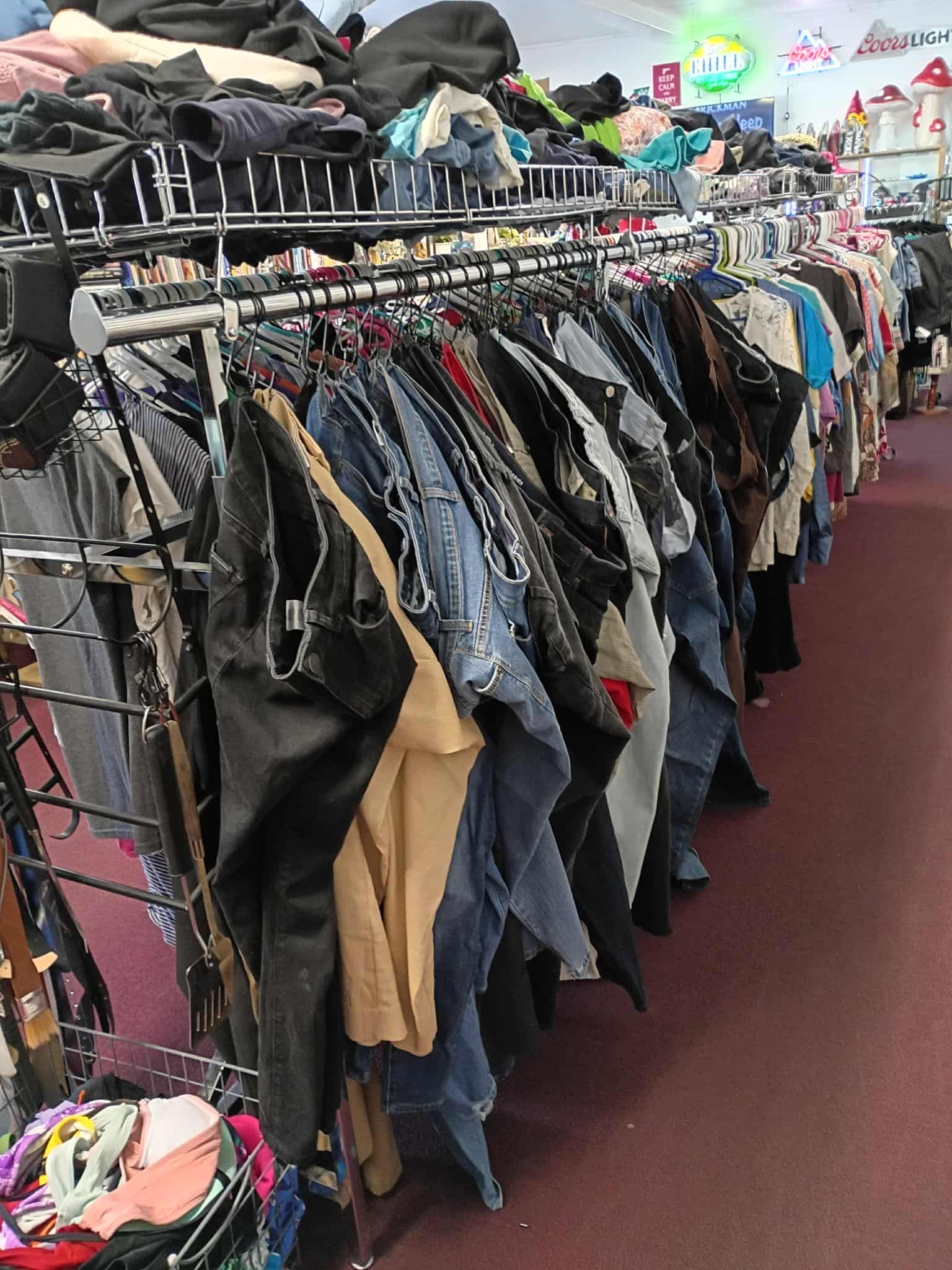 Clothes racks in a thrift store; jeans, jackets, shirts hang on racks in a shop.