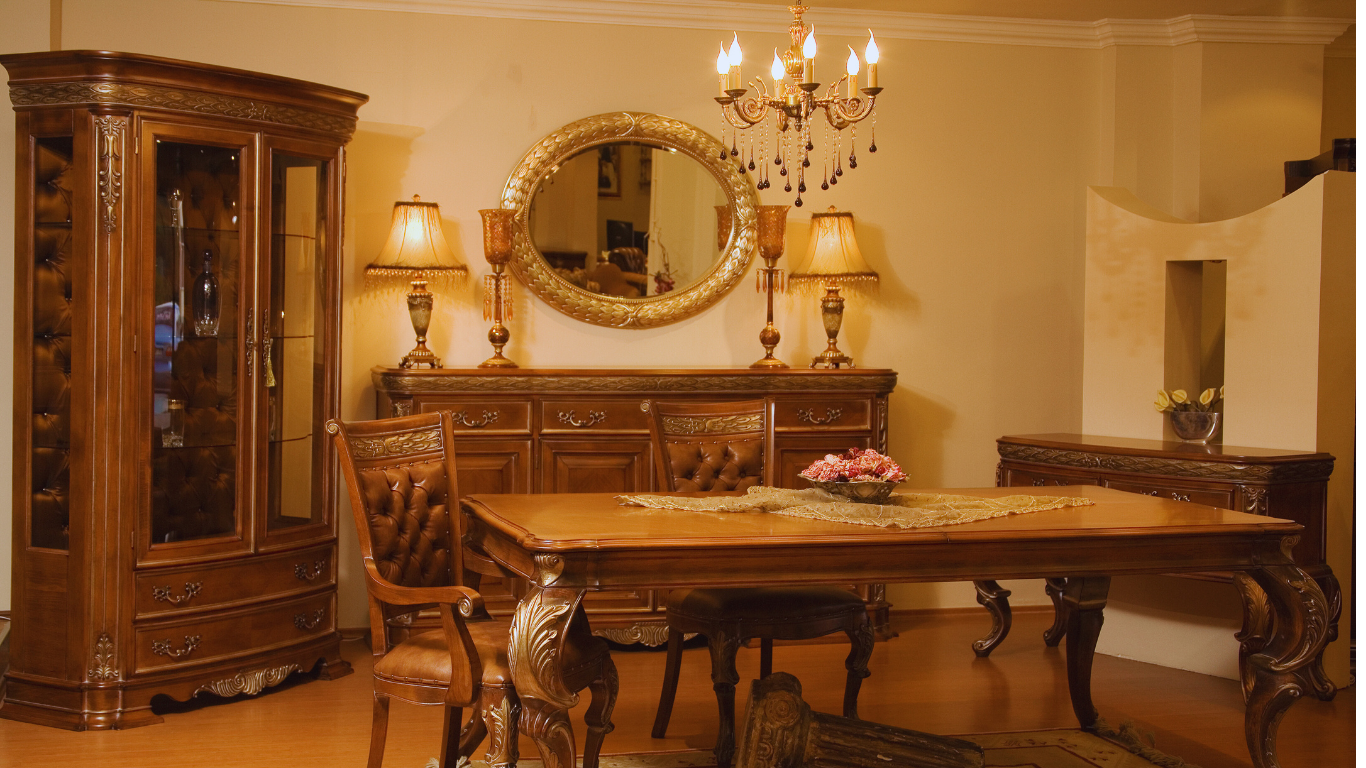 Elegant dining room with ornate wooden furniture, chandelier, and oval mirror.