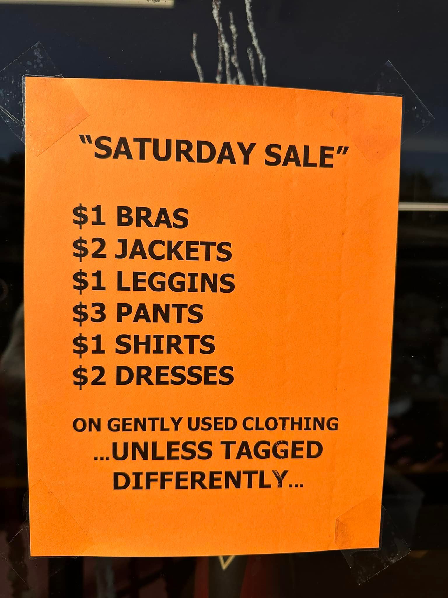 Orange sign: Saturday sale of gently used clothes. Prices listed: $1 bras, $2 jackets, etc.