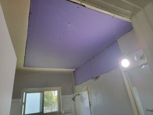 Construction worker with respirator and hard hat, smoothing plaster on a wall.