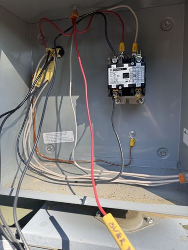 Person replacing a lightbulb in a black geometric pendant lamp, attached to a white ceiling.