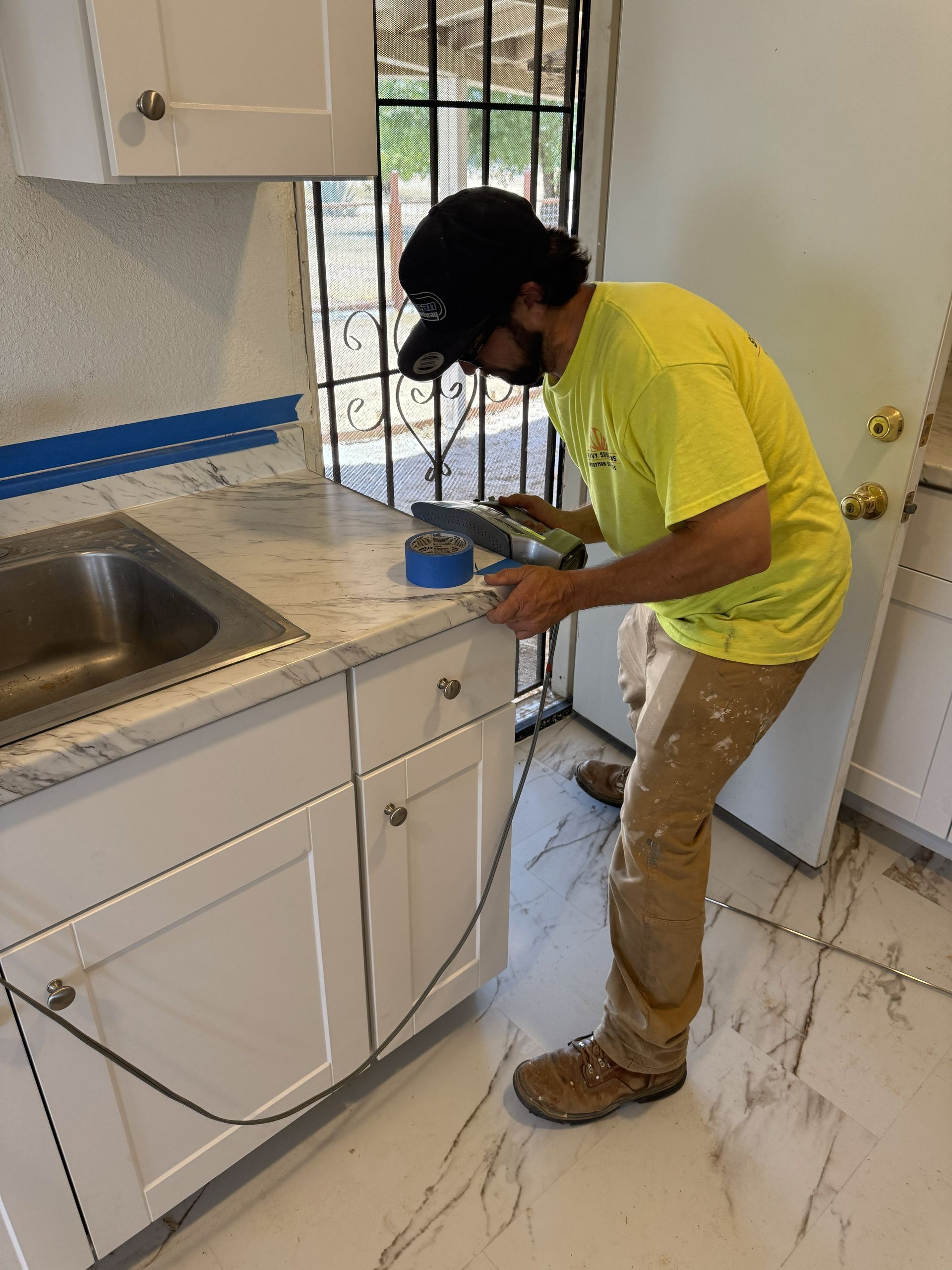 Person using a yellow drill to bore a hole in a wooden board in a well-lit workshop.