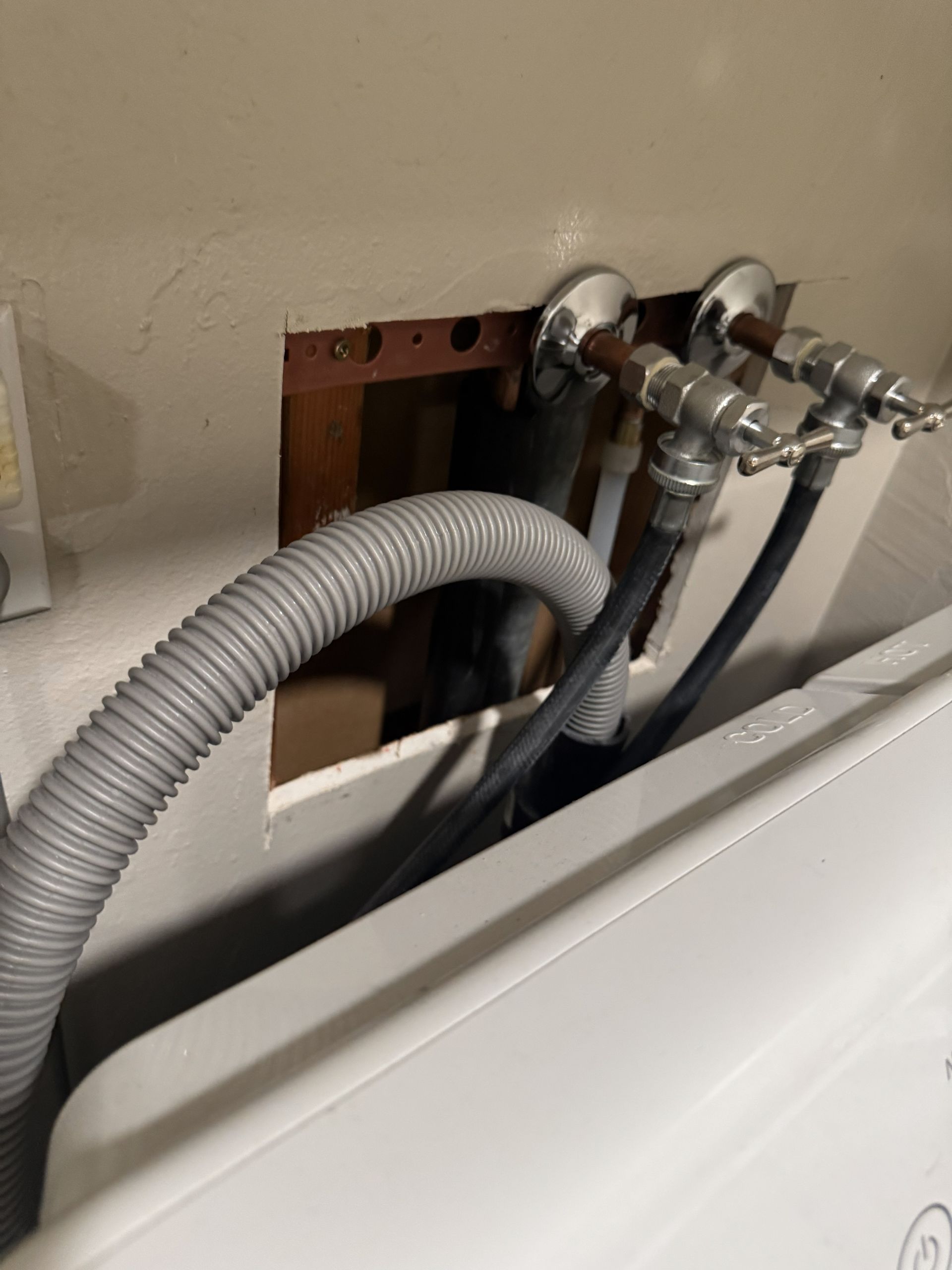 Hand turning on a chrome faucet in a bathroom, water flowing into the white sink.