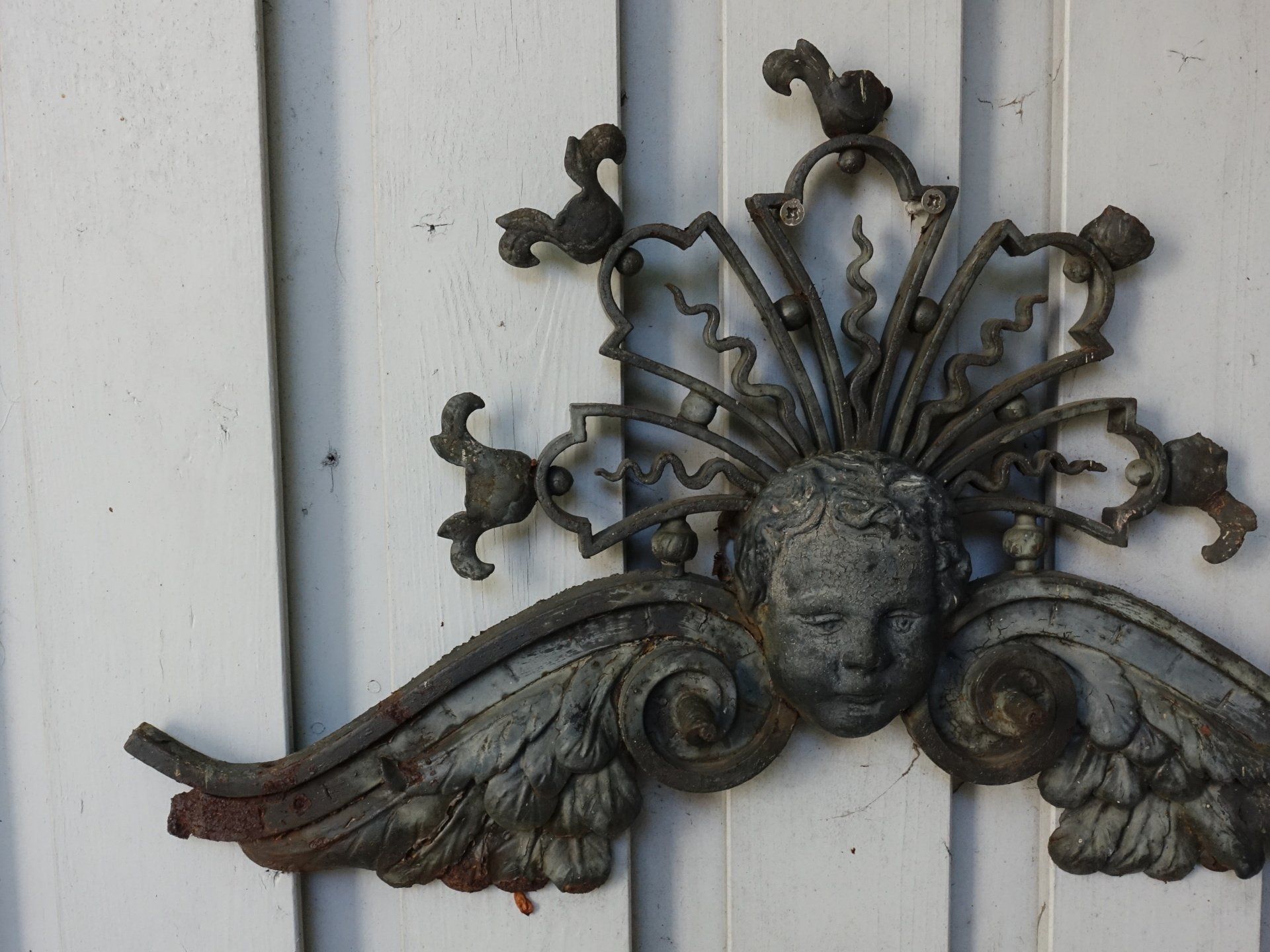 Ein Stück Metall mit einem Gesicht darauf hängt an einer weißen Wand