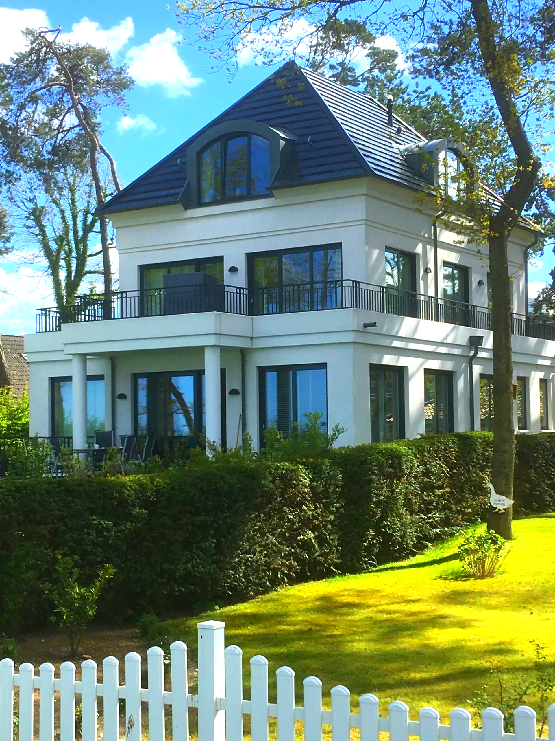 Ein großes weißes Haus mit einem weißen Lattenzaun davor