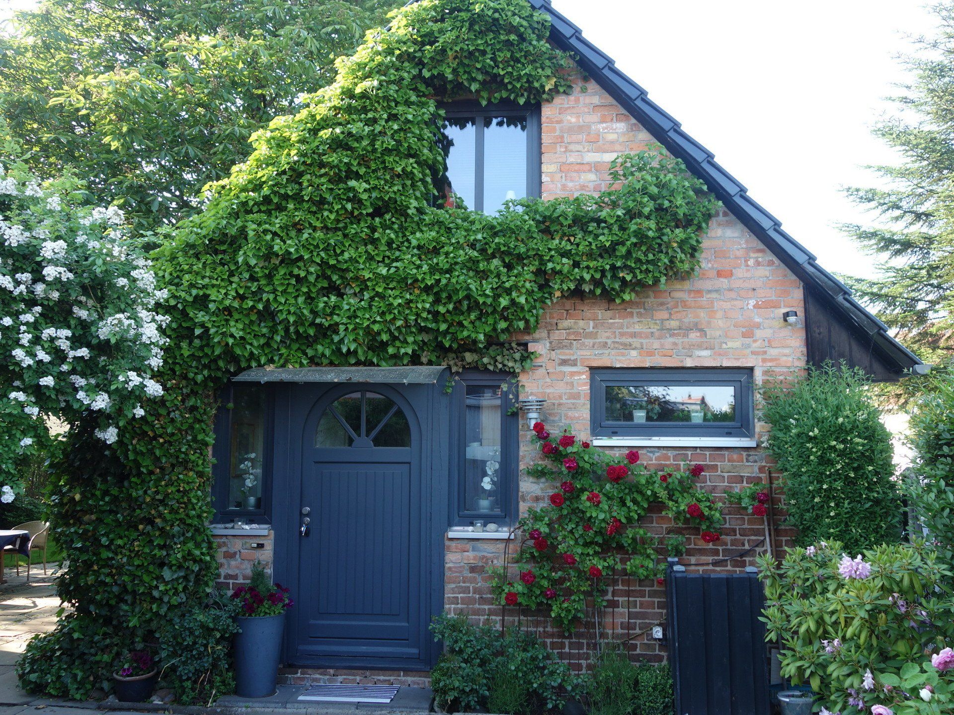 Ein Backsteinhaus mit einer schwarzen Tür und Efeu darauf