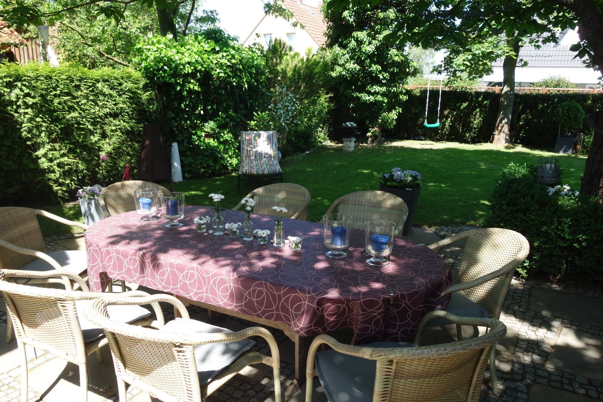 Ein Tisch und Stühle in einem Garten mit einer lila Tischdecke