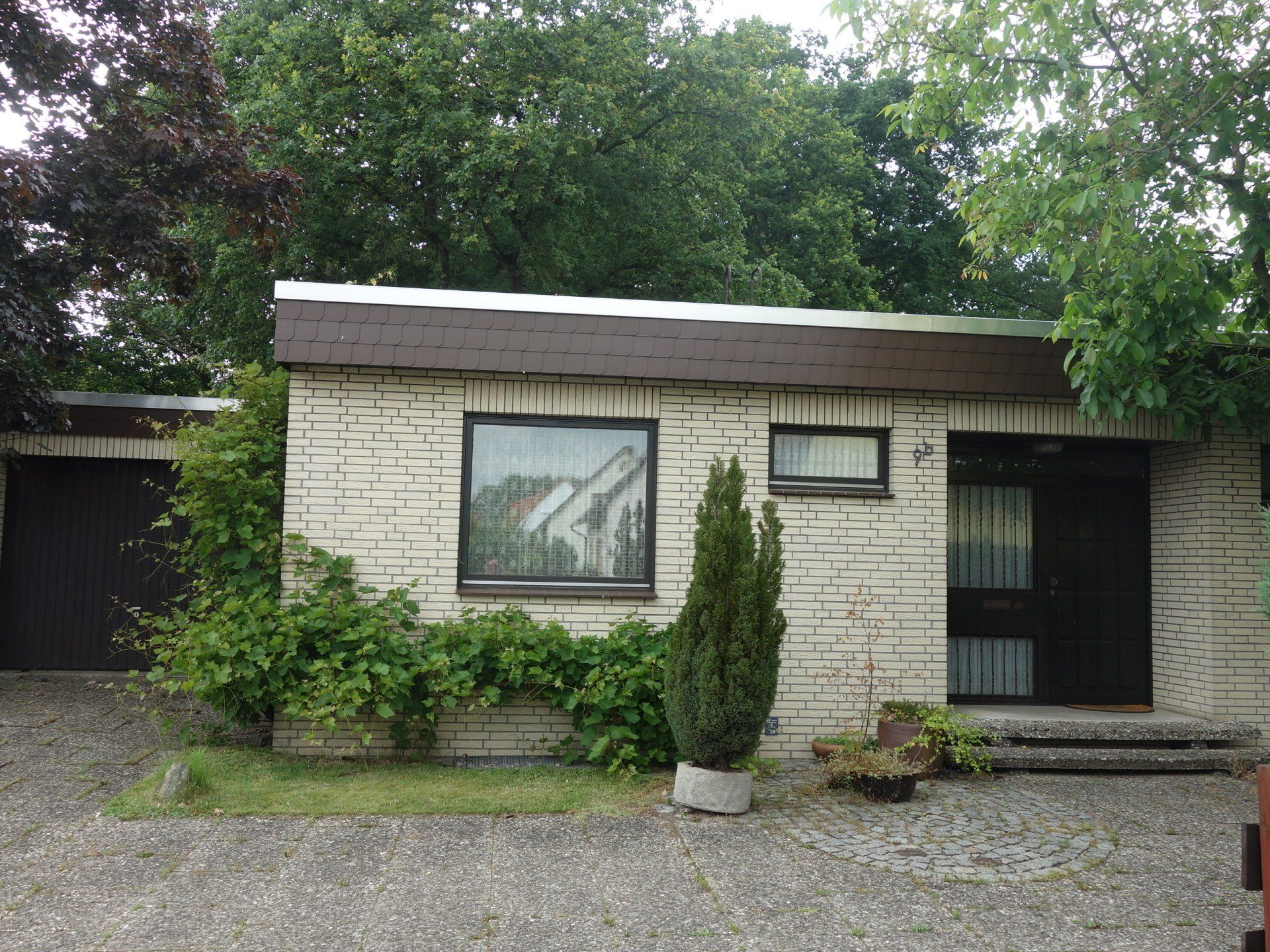 Ein kleines weißes Backsteinhaus mit Bäumen davor