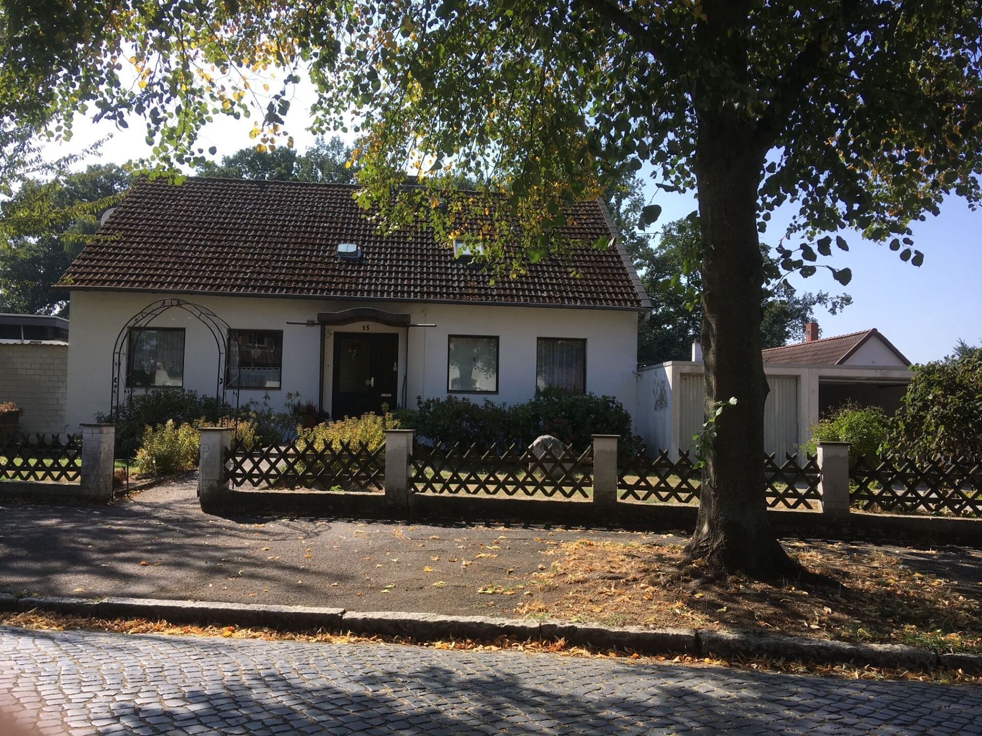 Ein weißes Haus mit einem Zaun und einem Baum davor