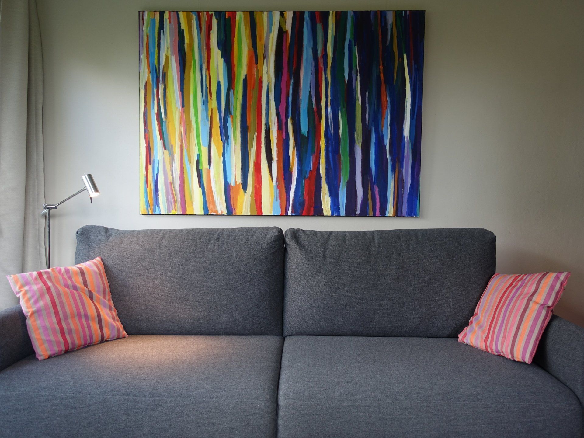 Ein Wohnzimmer mit einem Sofa und einem Gemälde an der Wand darüber.