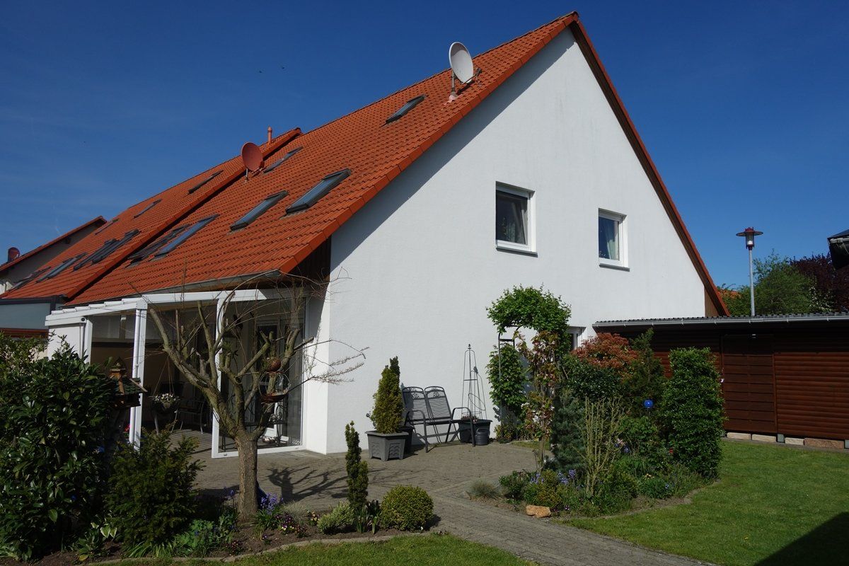 Ein weißes Haus mit einem roten Dach und einer Terrasse