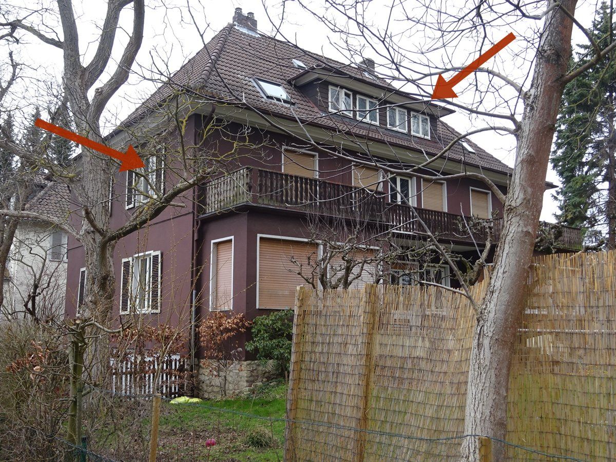 Ein Haus mit einem Zaun und Bäumen davor