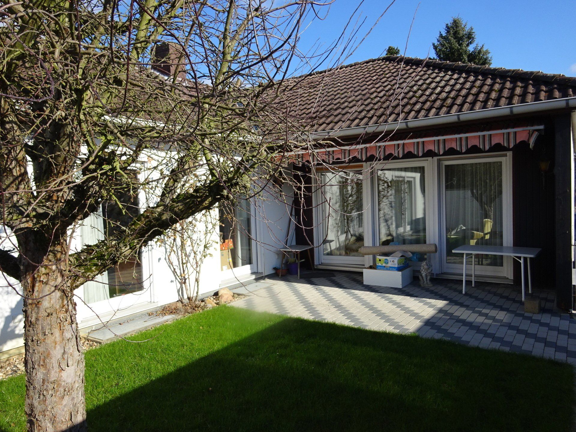 Ein Haus mit einer Terrasse und einem Baum davor