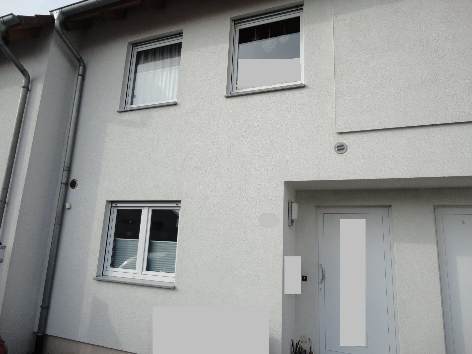 Ein weißes Haus mit zwei Fenstern und einer weißen Tür