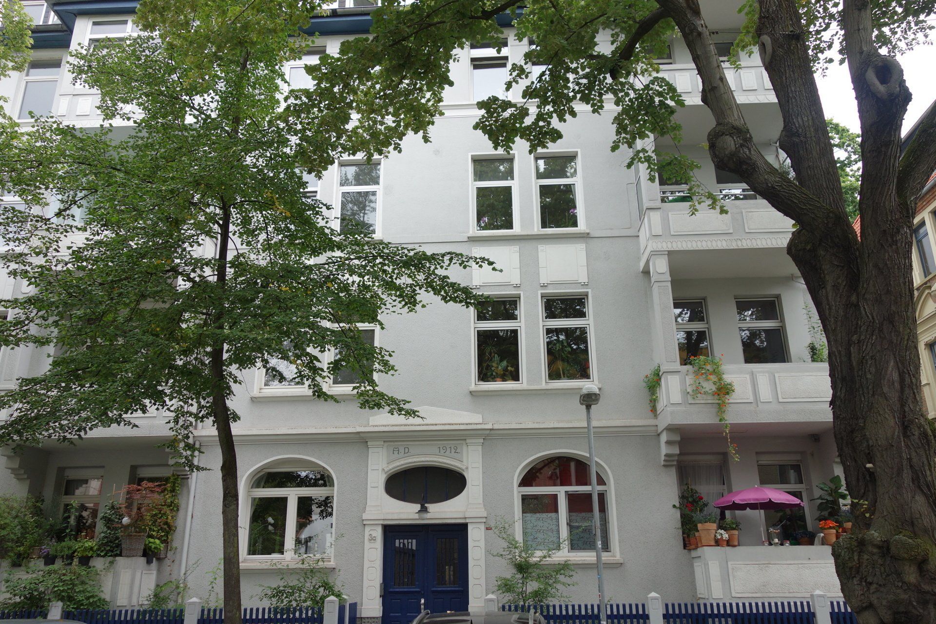 Ein weißes Gebäude mit einer blauen Tür ist von Bäumen umgeben