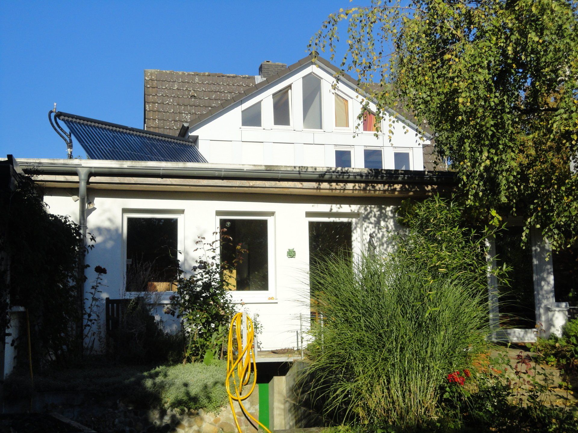 Ein weißes Haus mit einem Solarpanel auf dem Dach