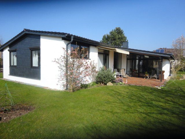 Ein weißes Haus mit einem schwarzen Dach ist von grünem Gras umgeben