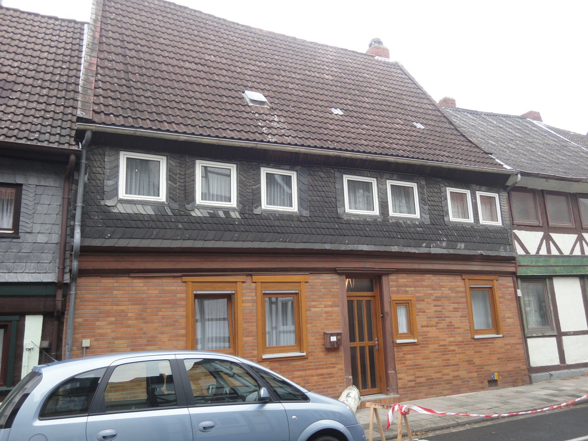 Vor einem Backsteingebäude parkt ein blaues Auto.