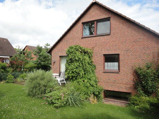 Ein rotes Backsteinhaus mit einem großen Rasen davor