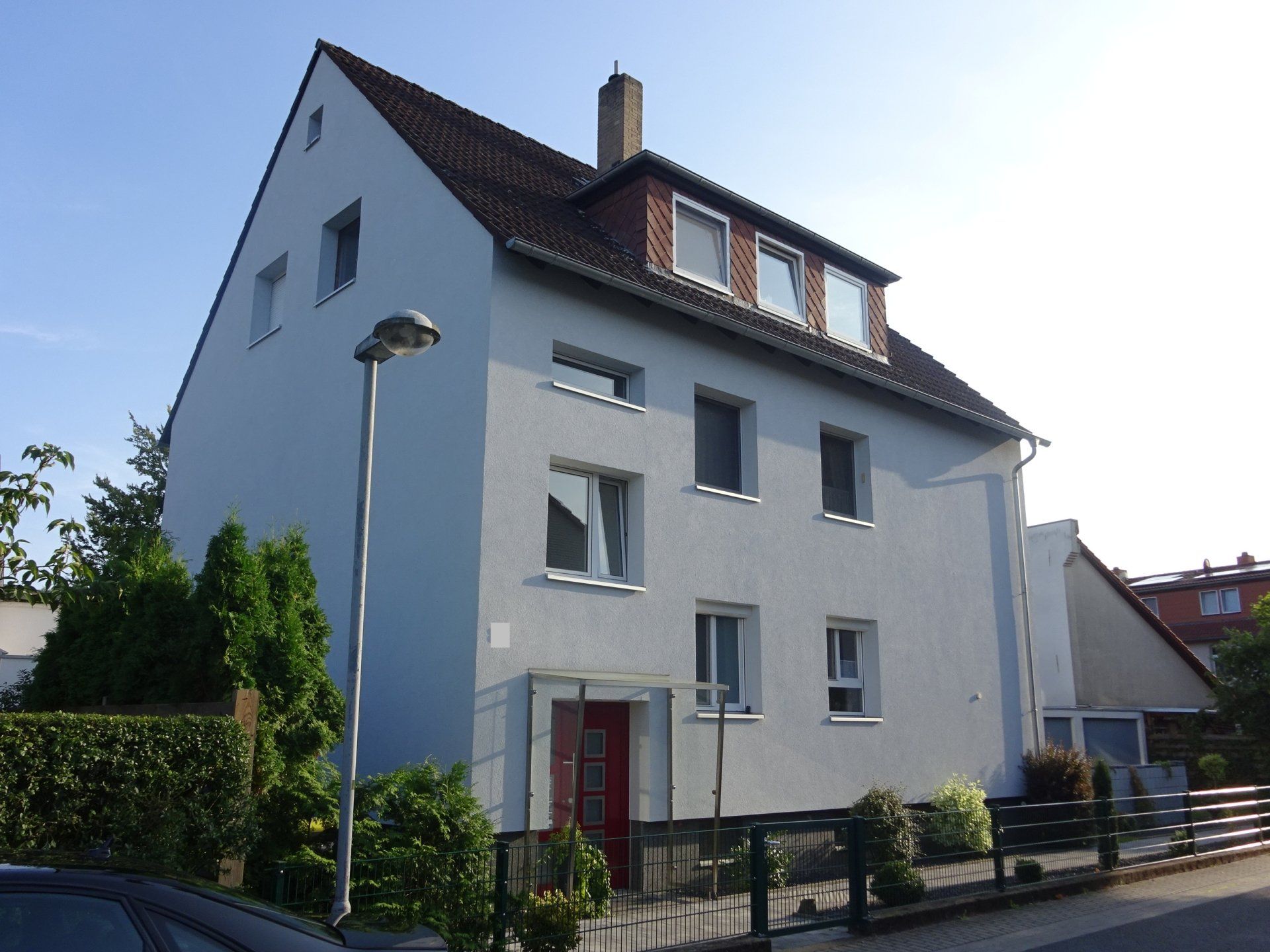 Ein weißes Haus mit einer roten Tür und einem schwarzen Dach