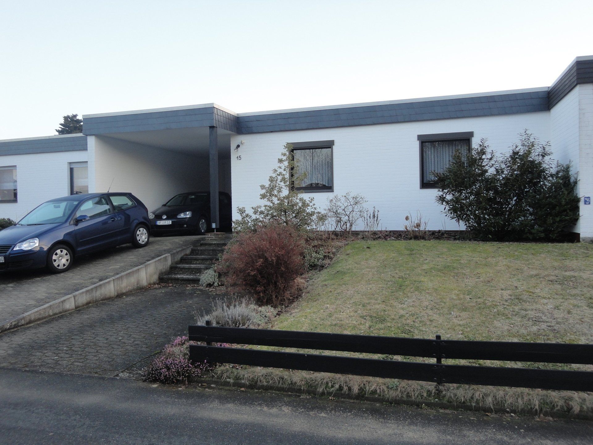 Ein blaues Auto steht vor einem weißen Haus