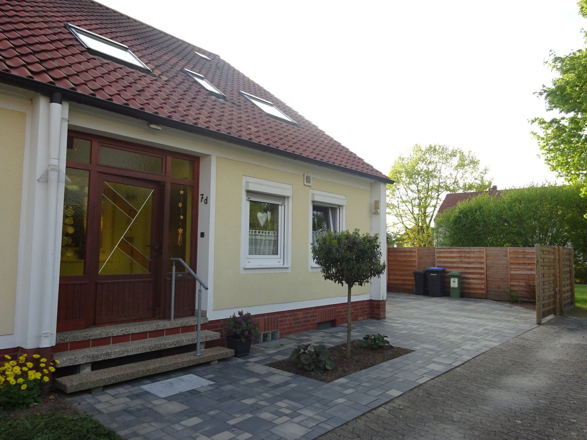 Ein gelbes Haus mit einem roten Dach und einem Baum davor.